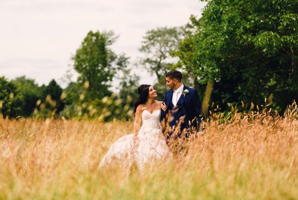 Shot of bride and groom walking through field by Northamptonshire wedding photographer Elliot W Patching