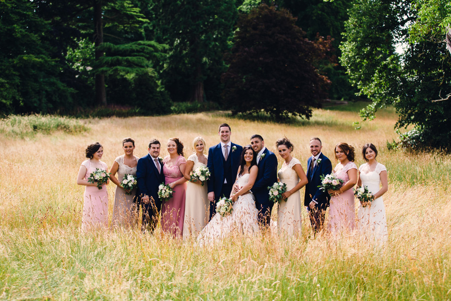 bride, groom & friends pose in fields - photographed by Courteen Hall wedding photographer