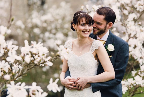 bride and groom with a backdrop of beautiful white flowers by Northamptonshire wedding photographer