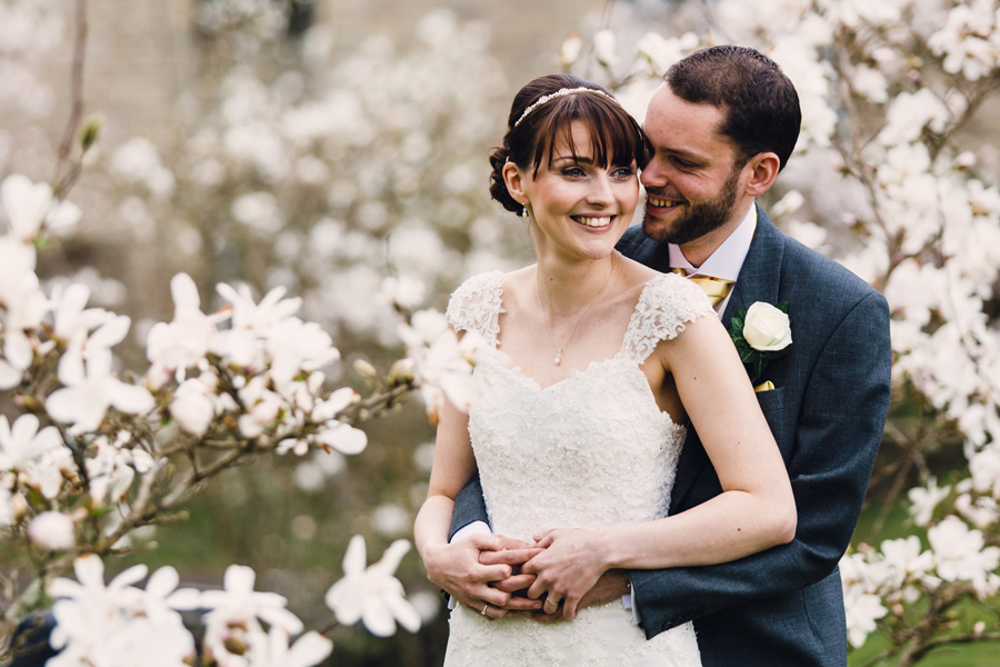 bride and groom with a backdrop of beautiful white flowers by Northamptonshire wedding photographer