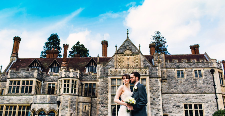 a bride and groom pose for photographs outside rhinefield house