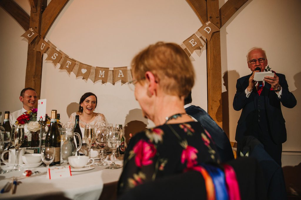 a bride laughs during a speech at her wedding