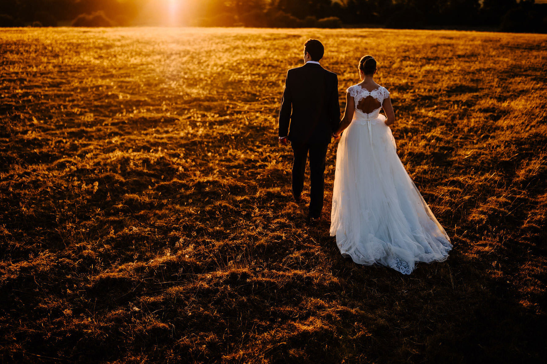 a bride and groom walking into the sunset