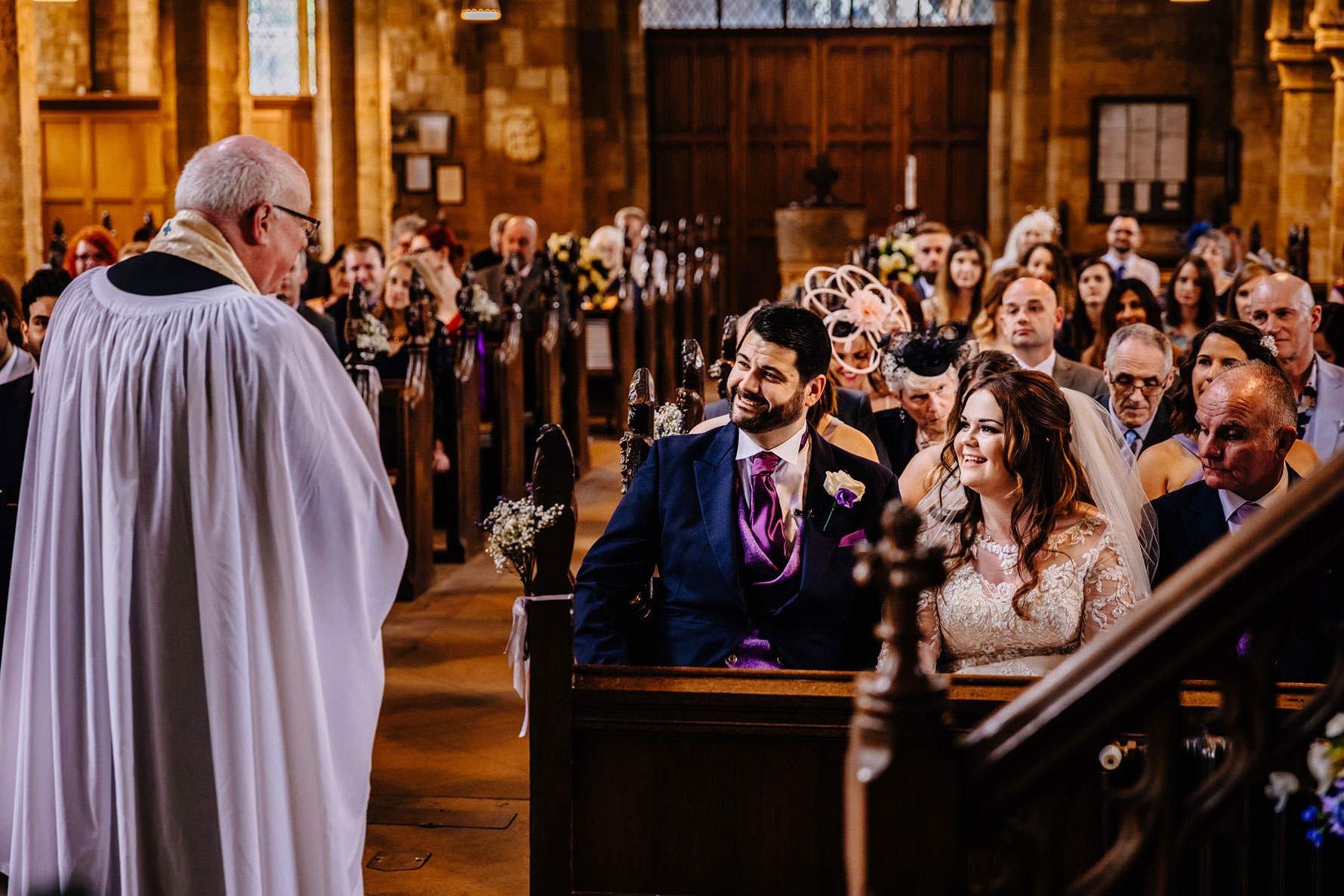 the bride and groom smiling at the vicar