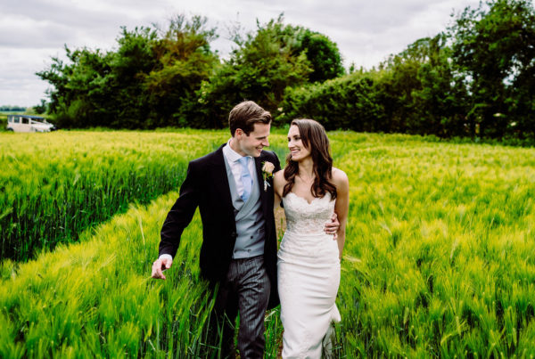 A bride and groom walk through a field at caswell house