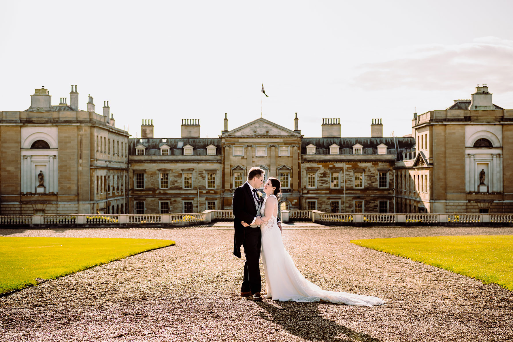 a bride and groom embrace in front of woburn abbey