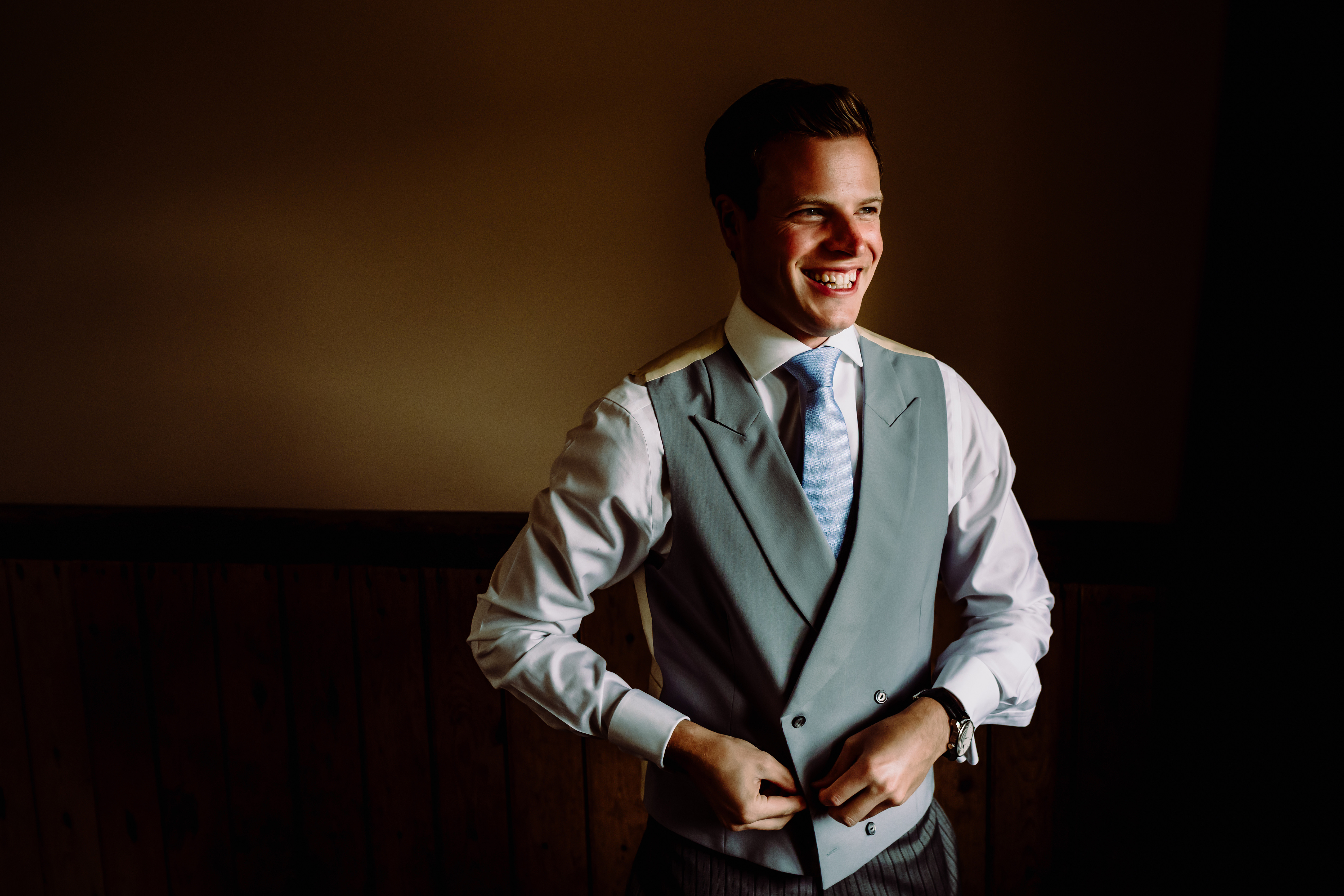 a groom doing up his waistcoat