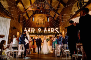 a bride and groom walk back up the aisle after being married at the great tythe barn