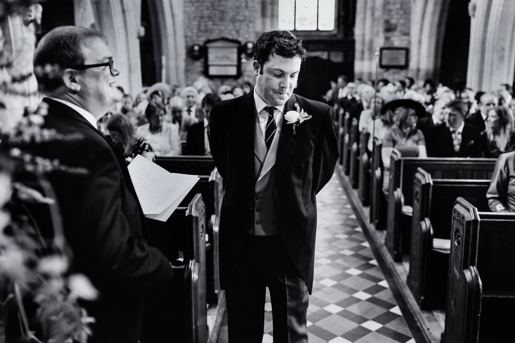 a groom stands nervously waiting for the bride